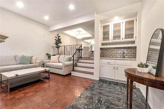 living room with sink, dark parquet floors, and a chandelier