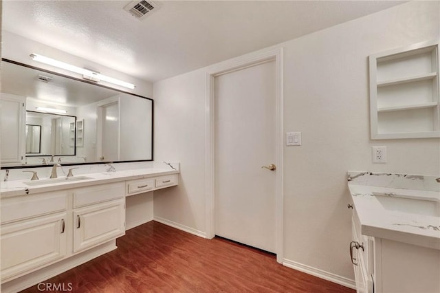 bathroom with wood-type flooring, vanity, and a textured ceiling