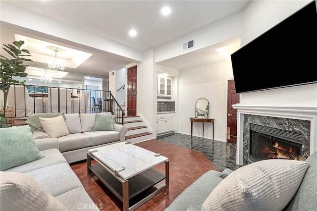 living room featuring dark parquet flooring, a chandelier, and a fireplace