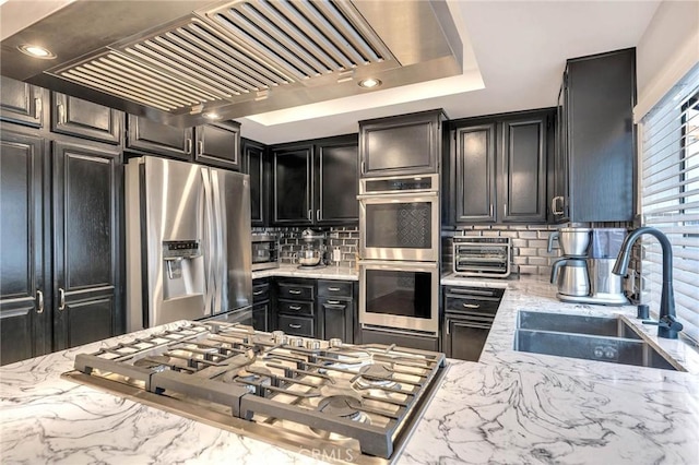 kitchen featuring sink, stainless steel appliances, custom range hood, and light stone countertops