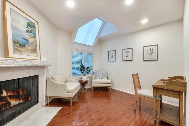 sitting room with wood-type flooring, a fireplace, and a skylight