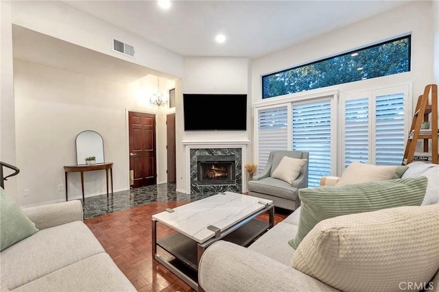 living room with a notable chandelier, parquet floors, and a premium fireplace