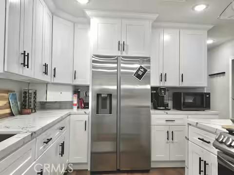 kitchen with light stone counters, white cabinets, and stainless steel appliances