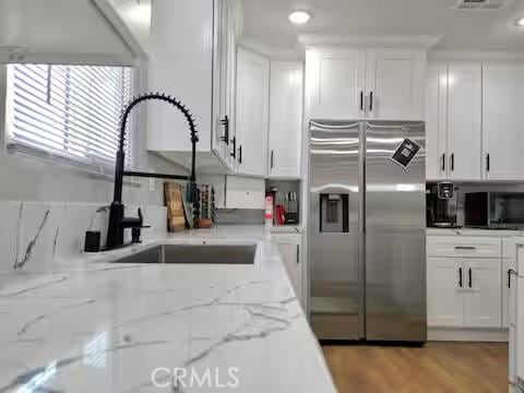 kitchen with sink, stainless steel appliances, light stone counters, and white cabinets