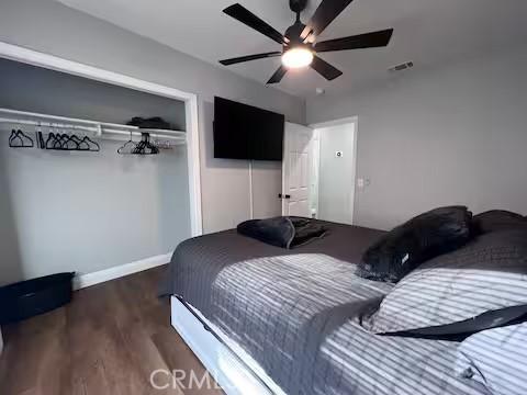 bedroom with ceiling fan, dark hardwood / wood-style floors, and a closet