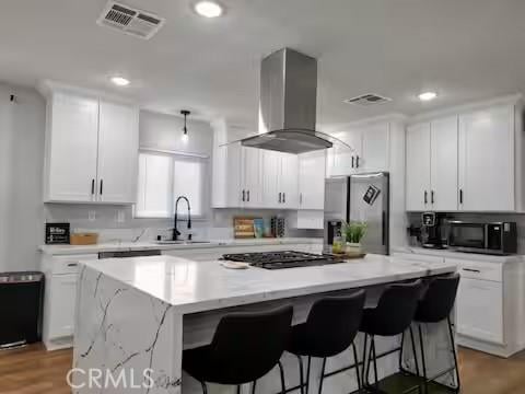 kitchen with stainless steel refrigerator with ice dispenser, sink, extractor fan, white cabinetry, and a center island