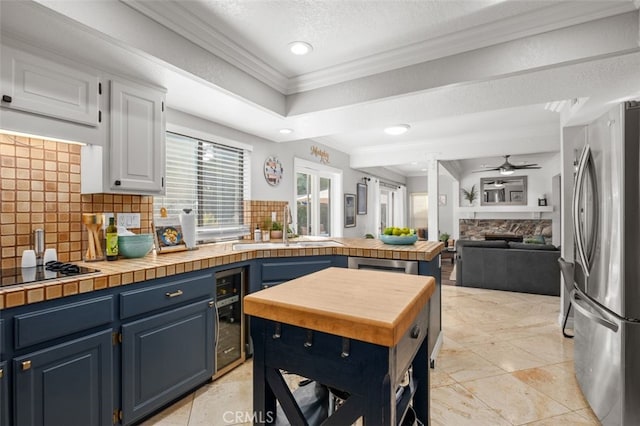 kitchen with blue cabinetry, a textured ceiling, stainless steel fridge, beverage cooler, and decorative backsplash