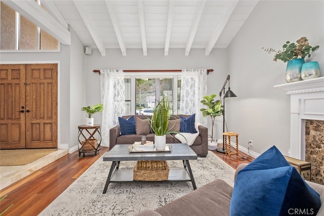 living room featuring hardwood / wood-style flooring, a high end fireplace, beam ceiling, and wooden ceiling