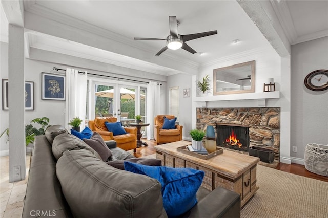 living room featuring a stone fireplace, hardwood / wood-style flooring, ceiling fan, crown molding, and french doors