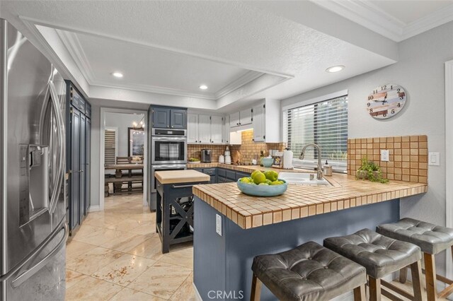 kitchen with tasteful backsplash, sink, a breakfast bar area, kitchen peninsula, and stainless steel appliances