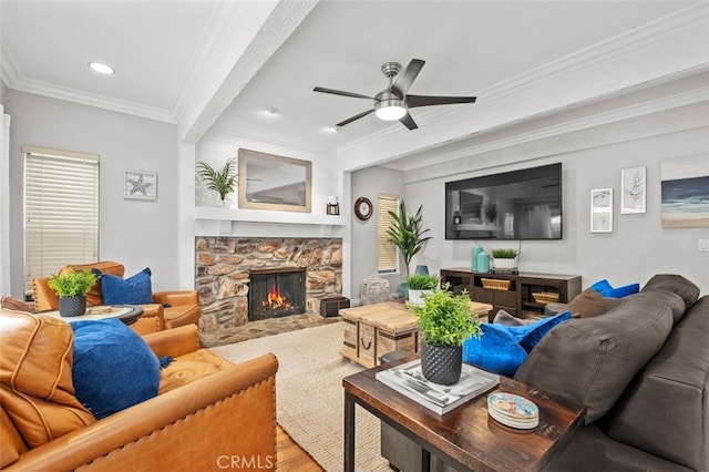 living room featuring hardwood / wood-style floors, a stone fireplace, ornamental molding, and ceiling fan