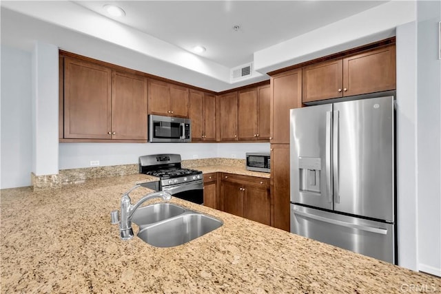 kitchen with light stone counters, sink, and stainless steel appliances