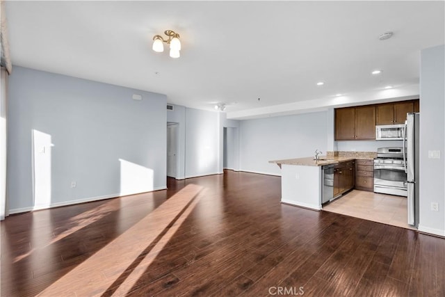 kitchen with light hardwood / wood-style floors, light stone counters, appliances with stainless steel finishes, and sink