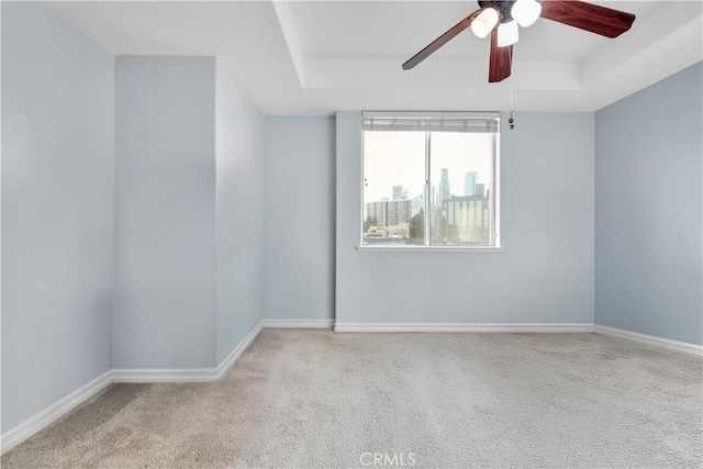 carpeted empty room featuring ceiling fan and a tray ceiling