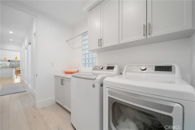 washroom featuring independent washer and dryer, cabinets, light hardwood / wood-style flooring, and a wealth of natural light