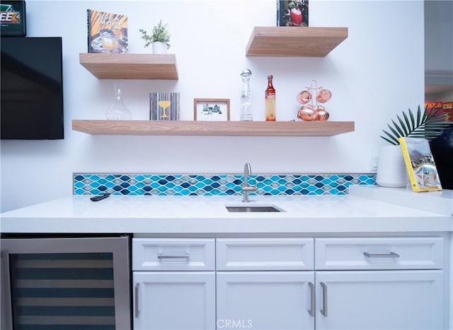 bar with sink, white cabinetry, and beverage cooler