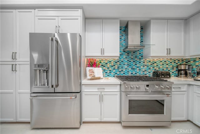 kitchen with wall chimney range hood, white cabinetry, tasteful backsplash, and high quality appliances