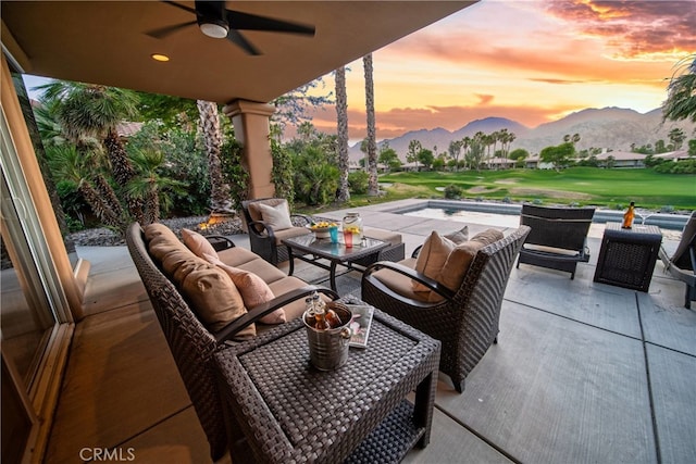 patio terrace at dusk featuring a mountain view, an outdoor living space, and ceiling fan