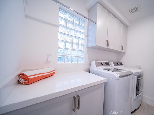 laundry area with cabinets, light wood-type flooring, and washing machine and clothes dryer