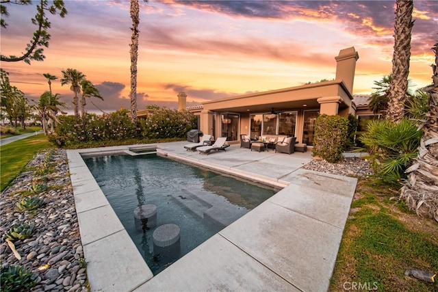 pool at dusk featuring a patio and an outdoor hangout area