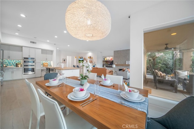 dining space with ceiling fan, sink, and light hardwood / wood-style flooring