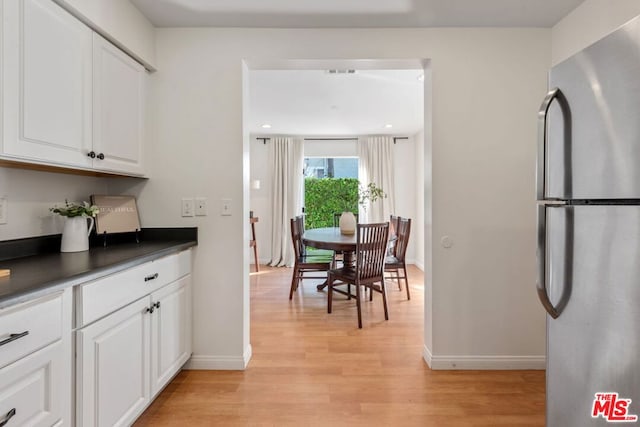 kitchen featuring white cabinets, stainless steel refrigerator, and light hardwood / wood-style flooring