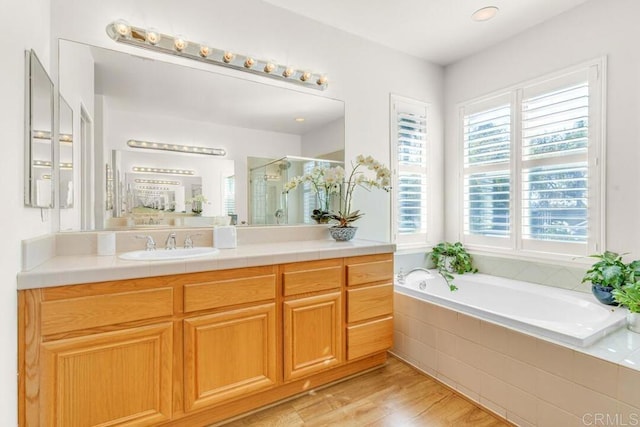 bathroom featuring wood-type flooring, separate shower and tub, and vanity