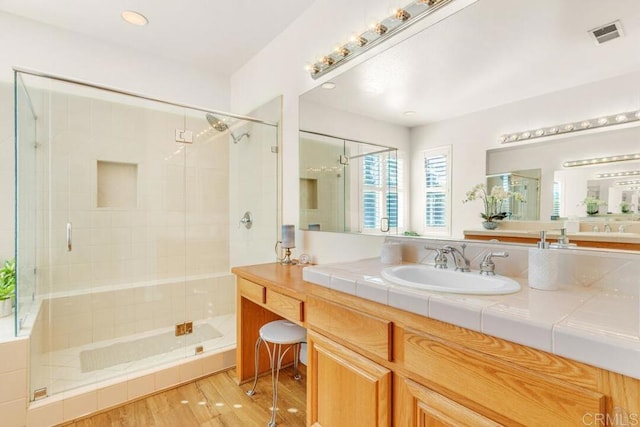 bathroom featuring vanity, hardwood / wood-style floors, and a shower with shower door