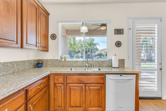 kitchen featuring sink, light hardwood / wood-style flooring, dishwasher, light stone countertops, and decorative light fixtures