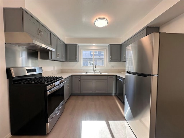 kitchen with sink, stainless steel appliances, light hardwood / wood-style floors, and gray cabinets