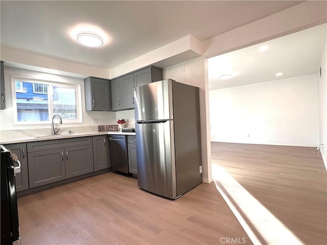 kitchen with sink, stainless steel appliances, gray cabinetry, and light wood-type flooring