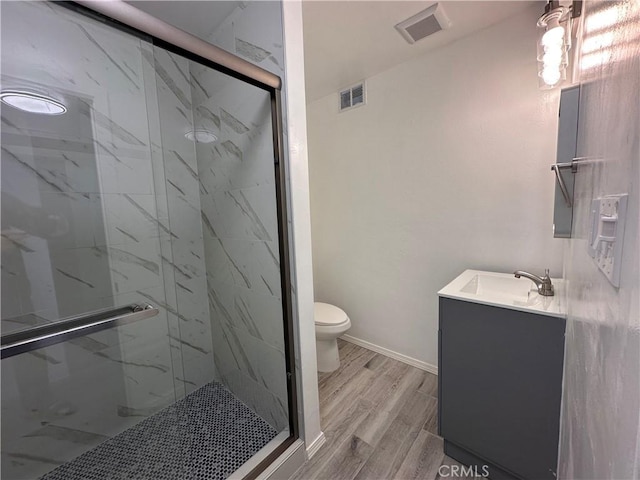 bathroom with wood-type flooring, a shower with door, toilet, and vanity