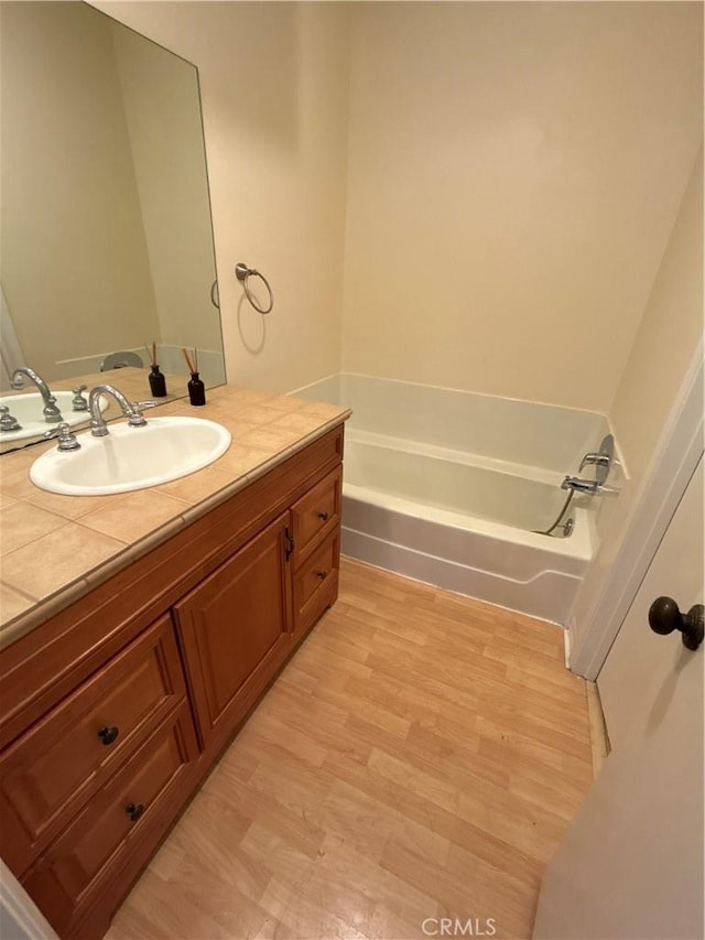 bathroom featuring hardwood / wood-style floors, a bathtub, and vanity