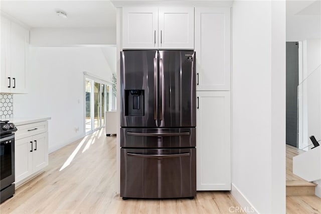 kitchen featuring backsplash, white cabinetry, light hardwood / wood-style flooring, and stainless steel appliances