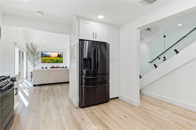 kitchen with light hardwood / wood-style floors, white cabinetry, range, and fridge with ice dispenser