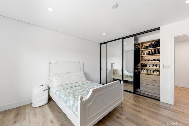 bedroom with light hardwood / wood-style floors and a closet