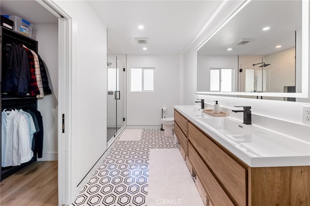 bathroom with hardwood / wood-style floors, walk in shower, vanity, and toilet