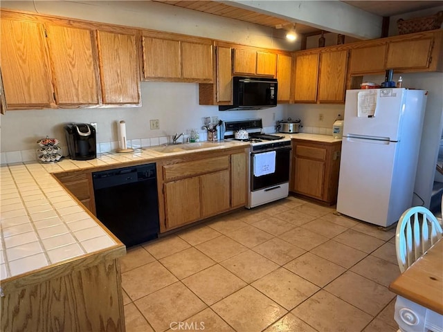 kitchen featuring sink, light tile patterned flooring, black appliances, and tile countertops