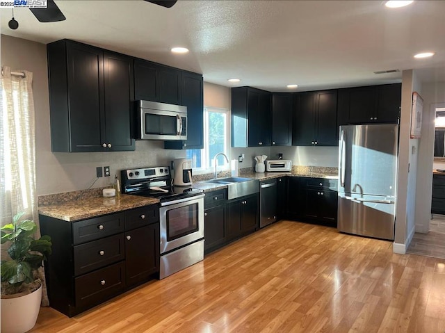 kitchen with light hardwood / wood-style floors, sink, light stone counters, and stainless steel appliances