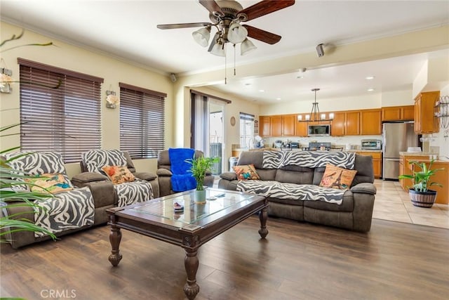 living room featuring light wood-type flooring, a toaster, a ceiling fan, and crown molding