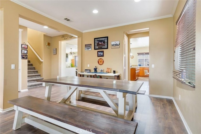 dining room with dark wood-style flooring, visible vents, ornamental molding, baseboards, and stairs