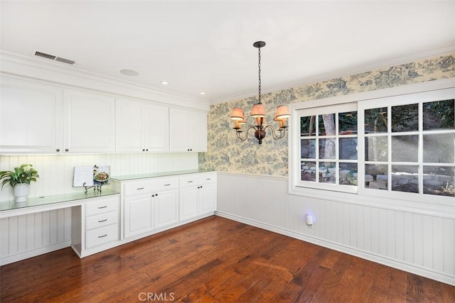 interior space with dark wood-type flooring, crown molding, built in desk, and an inviting chandelier