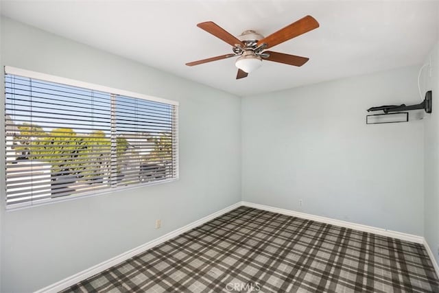 spare room featuring ceiling fan and dark colored carpet