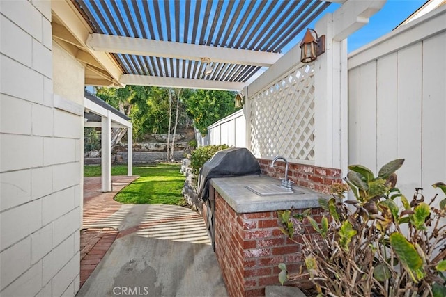 view of patio with area for grilling and a pergola