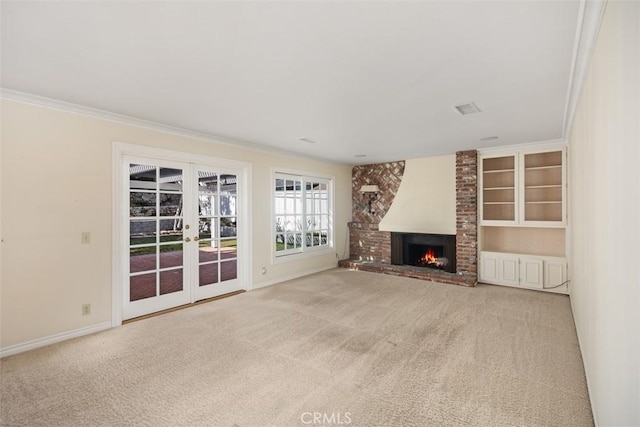 unfurnished living room featuring french doors, light colored carpet, ornamental molding, and a fireplace