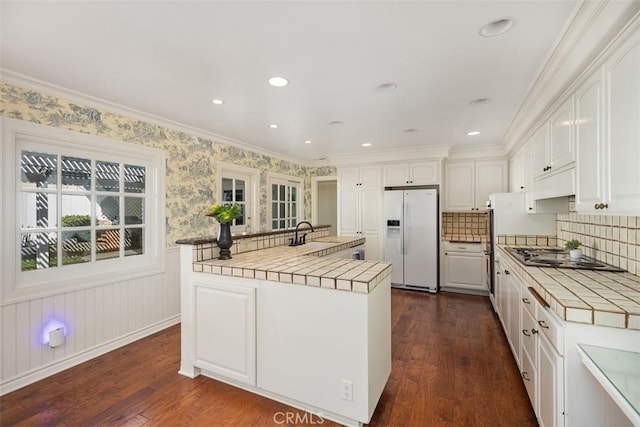 kitchen with tile counters, white cabinetry, and white refrigerator with ice dispenser