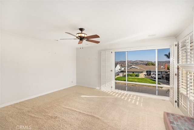 spare room with crown molding, light colored carpet, and ceiling fan