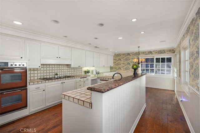 kitchen featuring pendant lighting, white cabinetry, and double oven