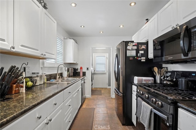 kitchen with white cabinetry, stainless steel appliances, sink, and dark stone counters