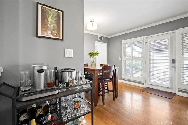 dining room with ornamental molding and light hardwood / wood-style flooring